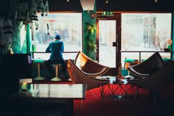 Photo by Thomas Litangen on Unsplash / cozy coffee shop with couches and a man sitting at the window / WLOY
